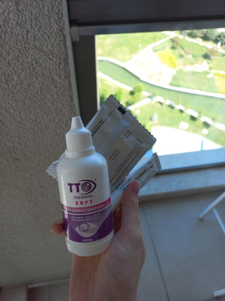 A hand holding eye-care products